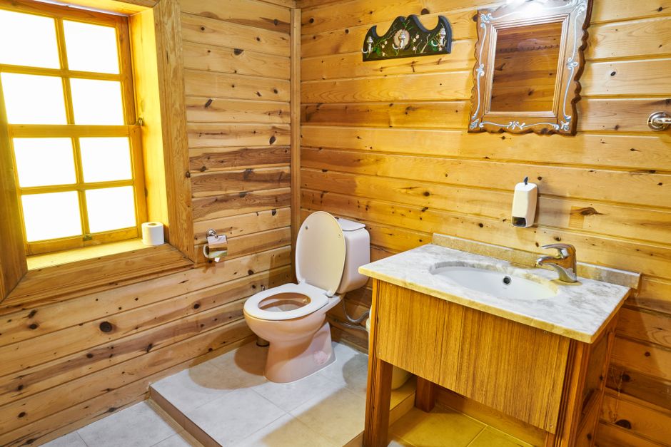 Rustic wooden bathroom with toilet and sink, representing composting toilet installations in backyard builds